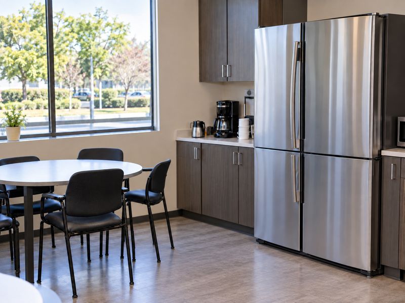 Clean office break room with a table, chairs and stainless steel refrigerator