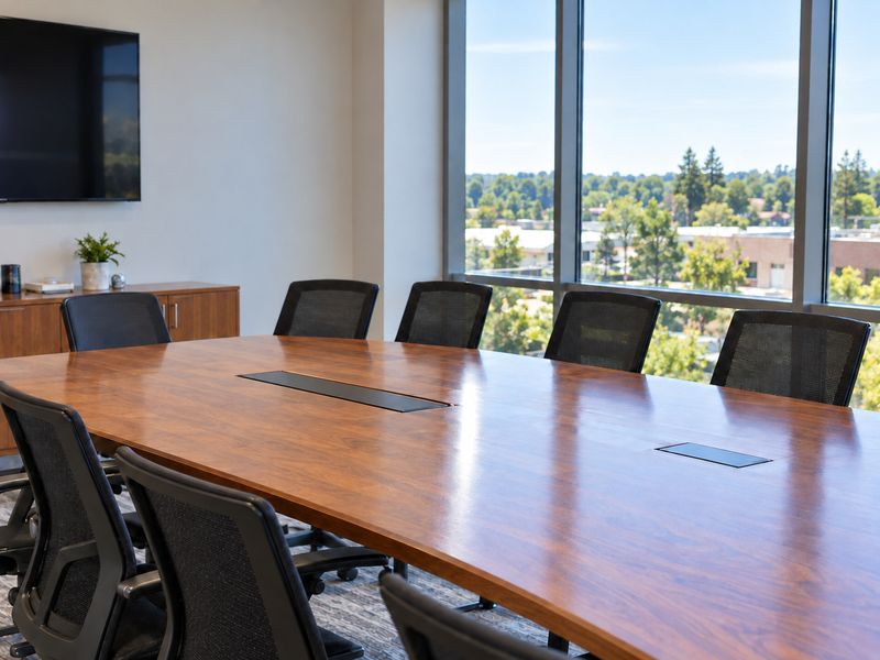 Clean conference room with a long wooden table and black chairs